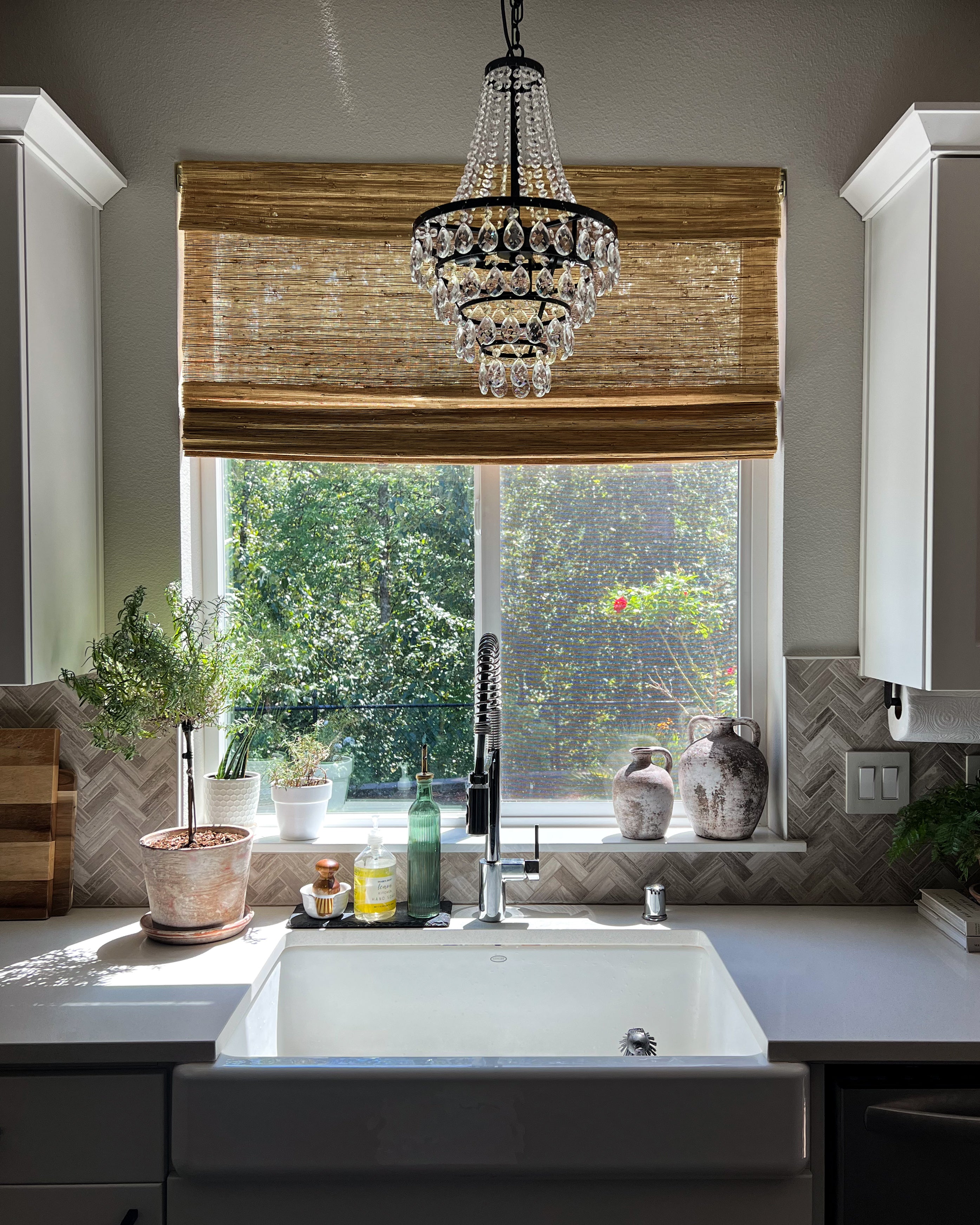 Custom sand Mia Jute Woven Shade installed on a sunny kitchen window, offering natural light and privacy above a farmhouse sink.