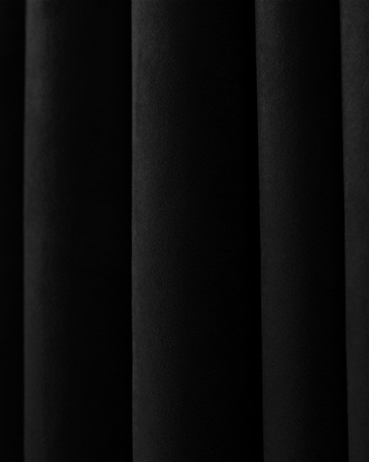 Close-up of deep black Moonlit Velvet custom curtain fabric with elegant folds, highlighting plush texture for blackout drapery.
