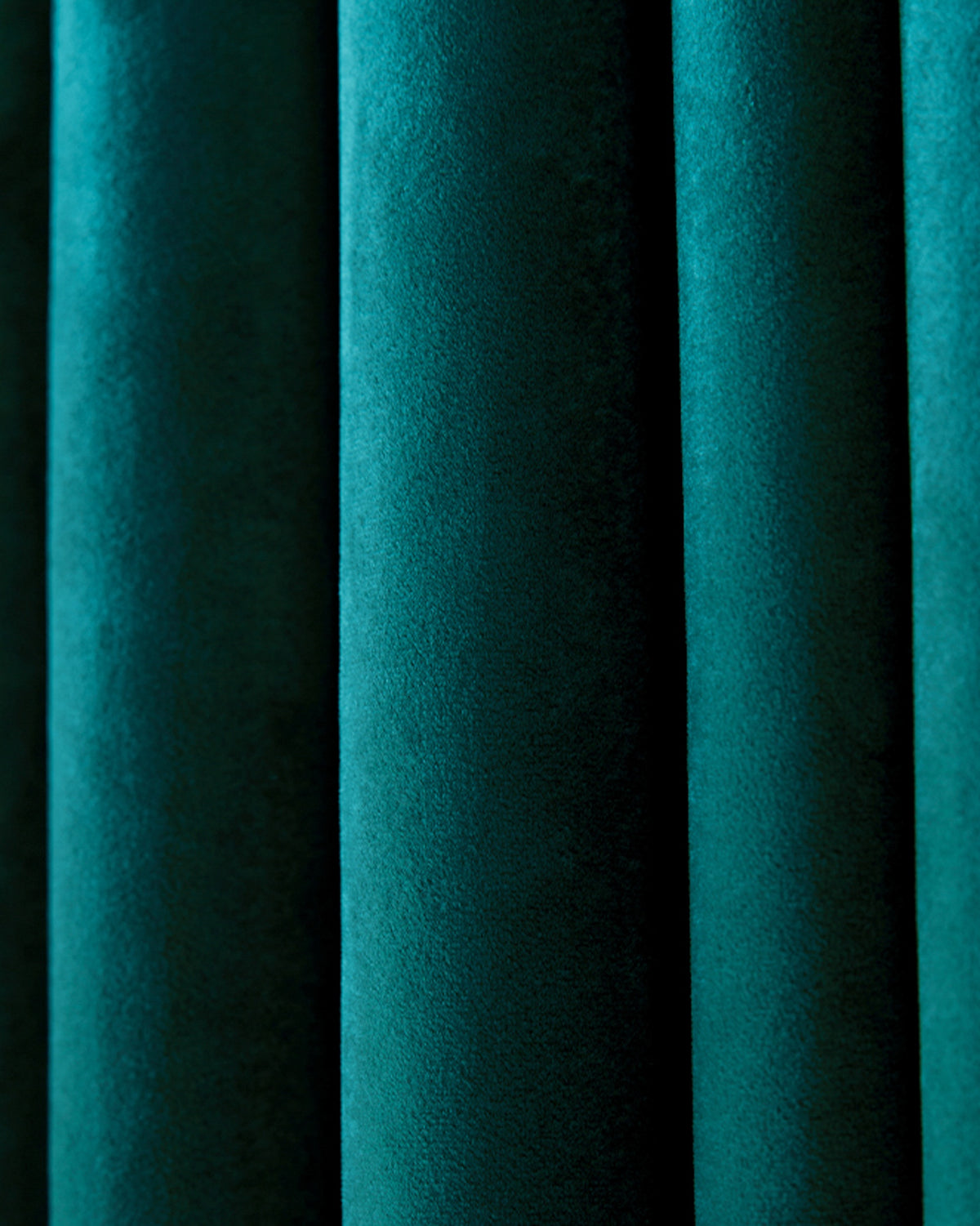 Close-up of deep teal luxury velvet custom drapery, highlighting the soft texture and elegant folds of the fabric.