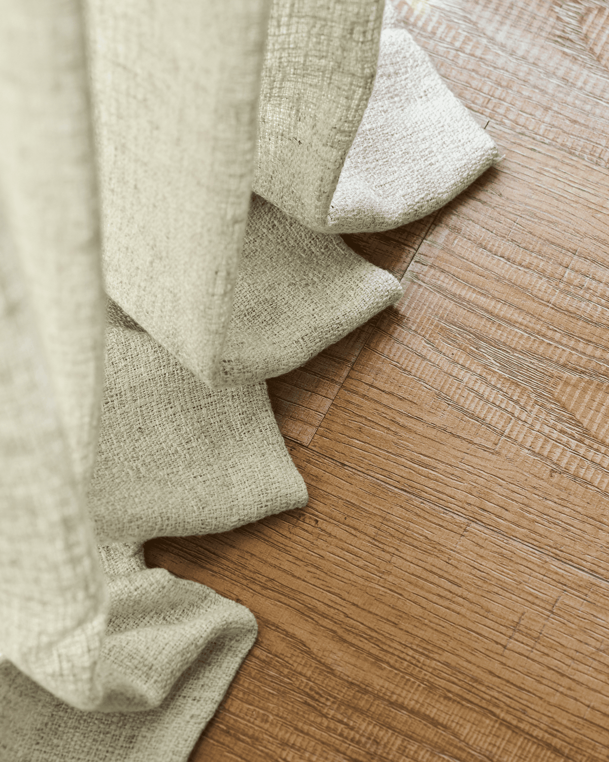 Fiona linen blend custom curtain, light beige, showing its beautiful natural textured weave draped on warm hardwood flooring.