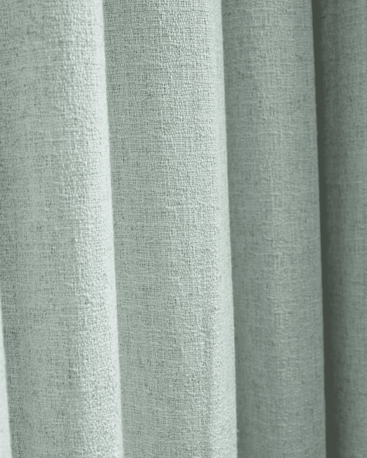 Close-up of the light, textured Fiona Linen Blend custom curtain fabric, showing its intricate weave and elegant vertical folds.