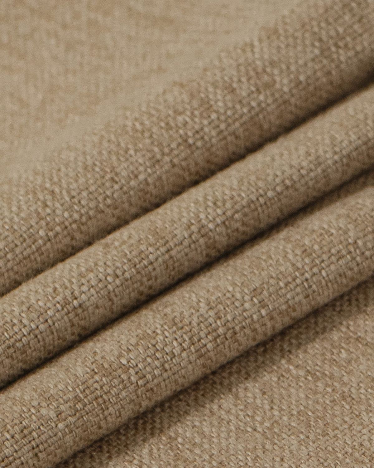 Close-up of sand-colored heavyweight linen fabric, showing its textured weave and folds for custom thermal, soundproof blackout drapes.