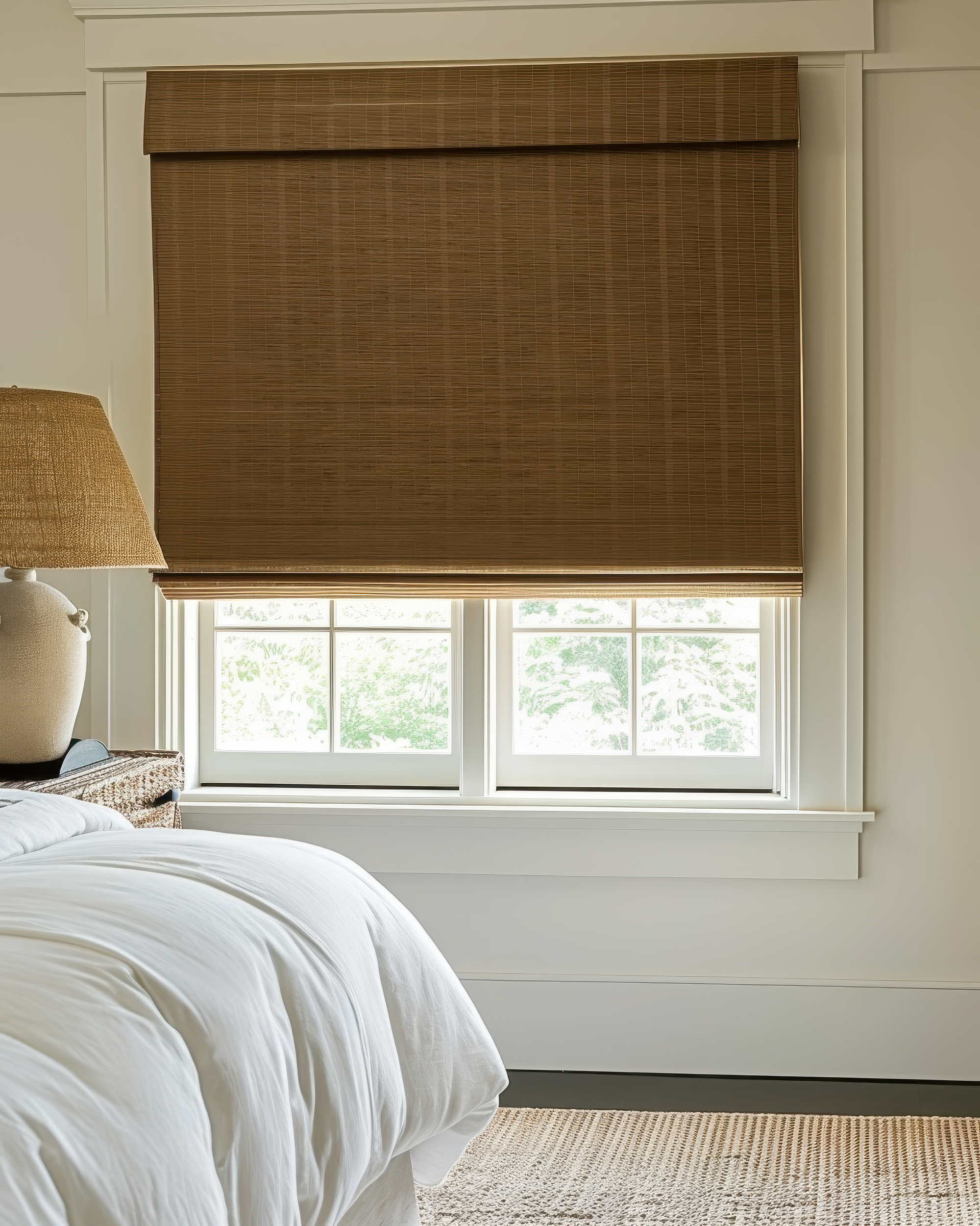 Tan Hana Bamboo Motorized Woven Shade installed on a bedroom window, a stylish custom window treatment for privacy & light control.