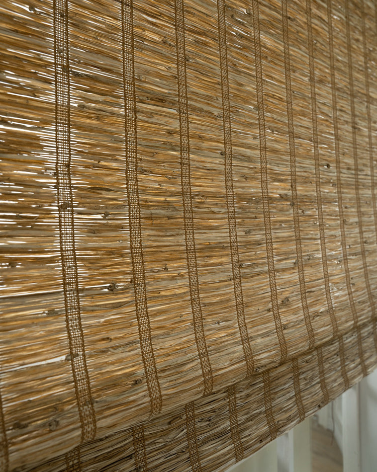 Close-up of Rumi Hay jute woven shade from TheHues, showing natural light brown fibers with vertical ladder weaves, perfect for custom window treatments.