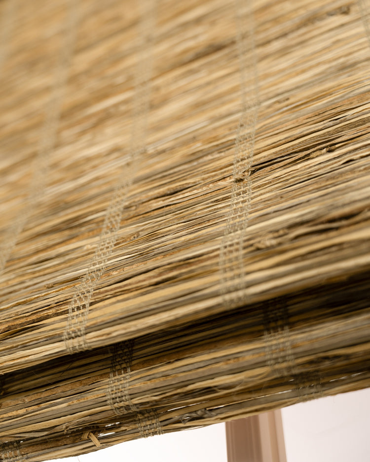 Detailed view of Rumi Jute Woven Shade in Straw, highlighting its natural straw texture, intricate weave, and layered window treatment design.