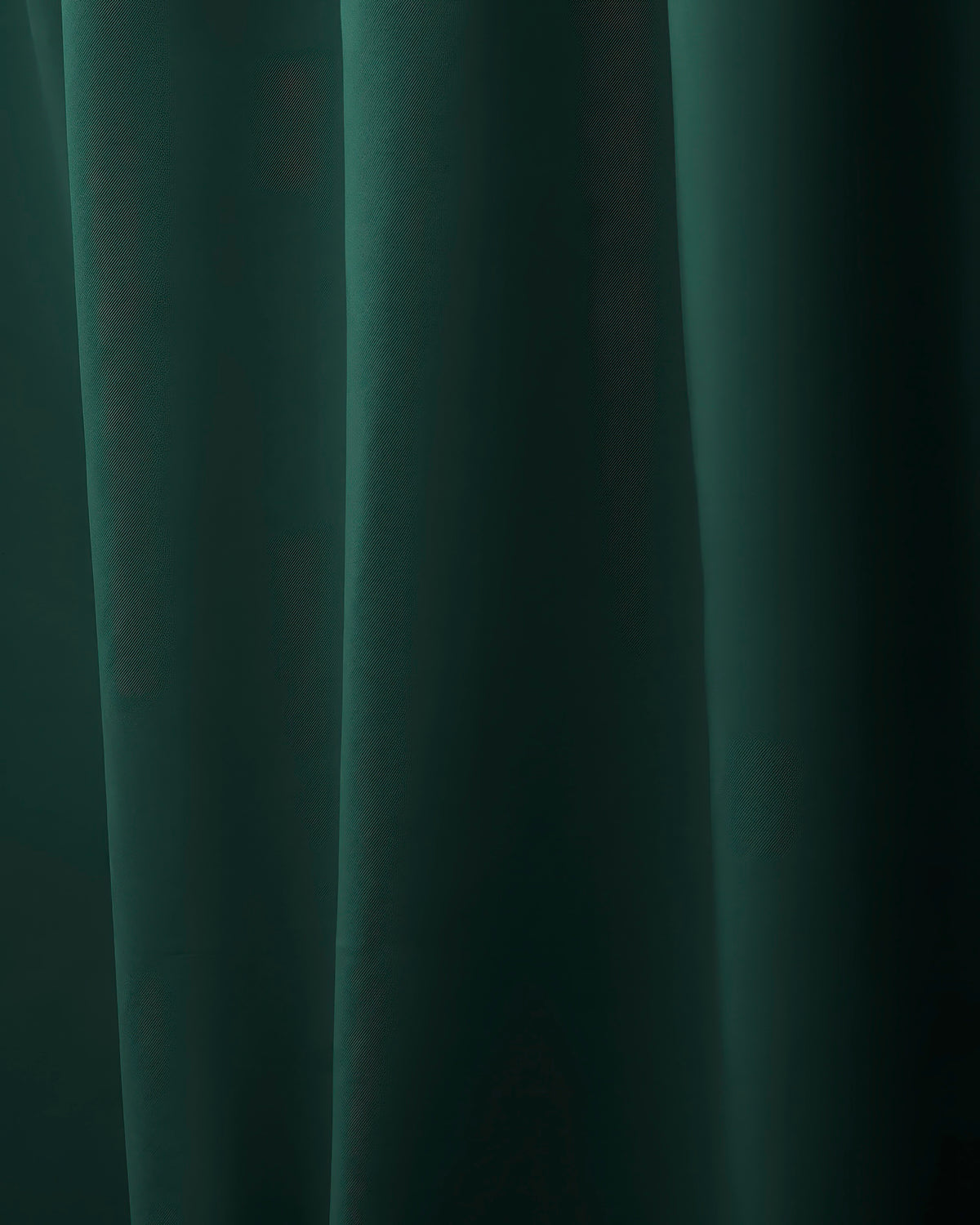 Detailed view of a deep green custom curtain fabric, showing soft drapes and subtle texture for a luxurious feel.