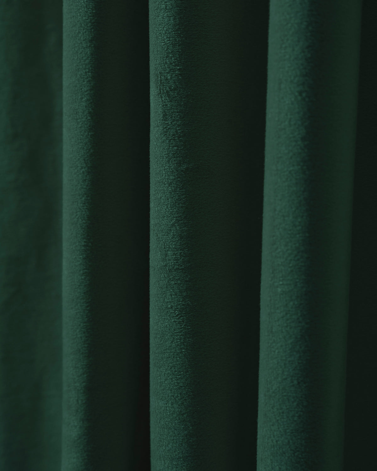 Close-up of lush dark green velvet custom curtain, highlighting its plush texture and heavyweight thermal blackout fabric for privacy.