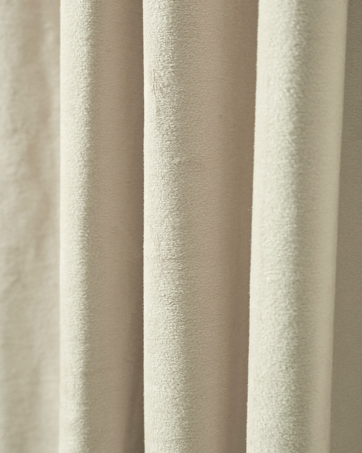 Close-up of luxurious, heavyweight beige velvet custom blackout curtain fabric, revealing its plush texture and soft folds.