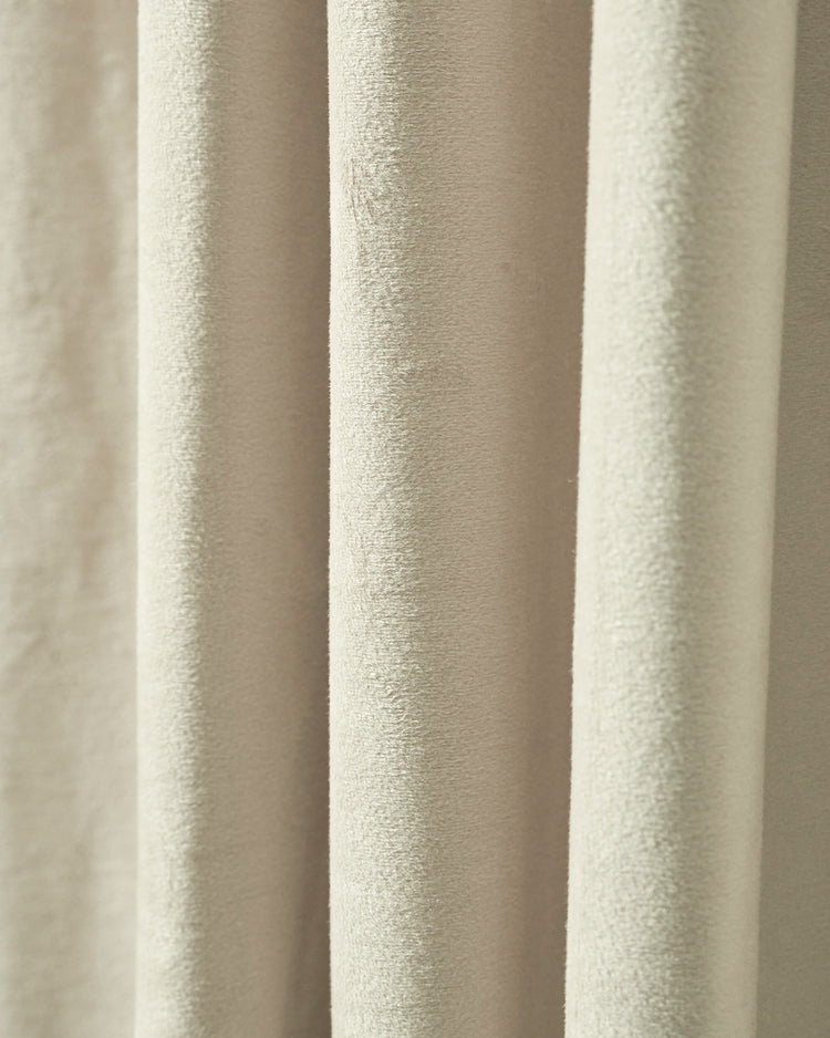 Close-up of luxurious, heavyweight beige velvet custom blackout curtain fabric, revealing its plush texture and soft folds.