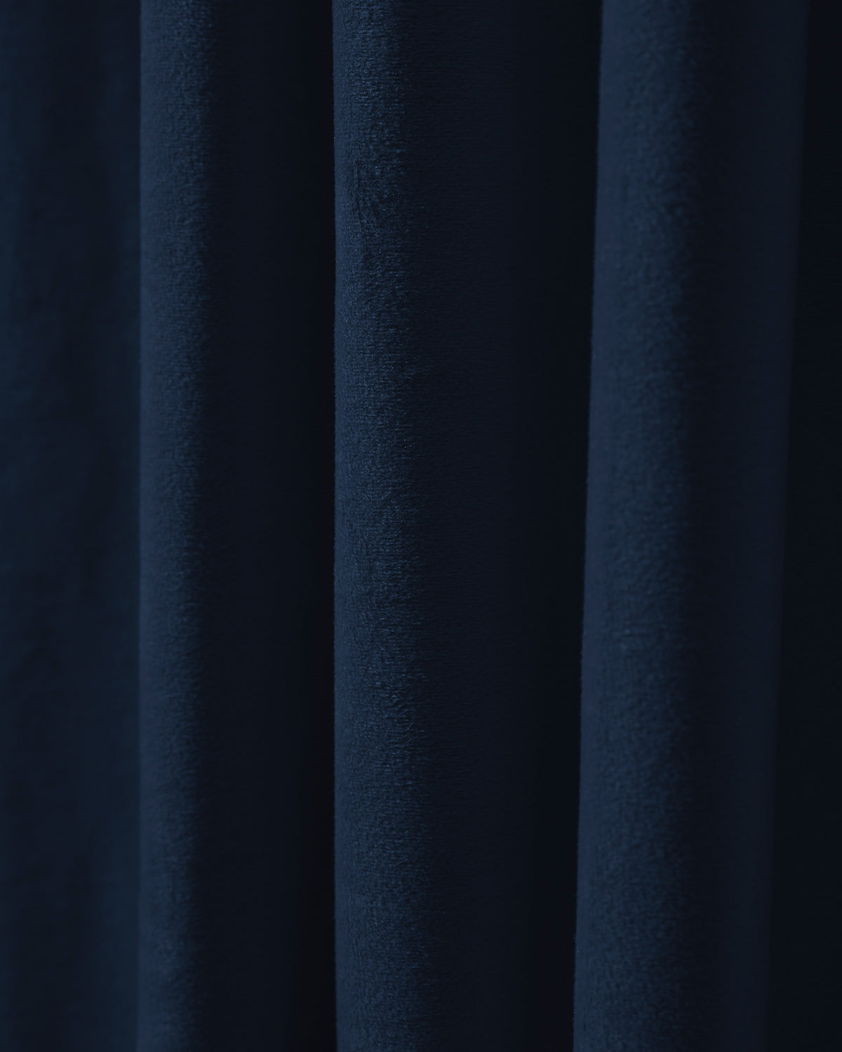 Close-up of luxurious navy velvet fabric, showcasing its rich texture and deep folds for heavyweight custom blackout curtains.