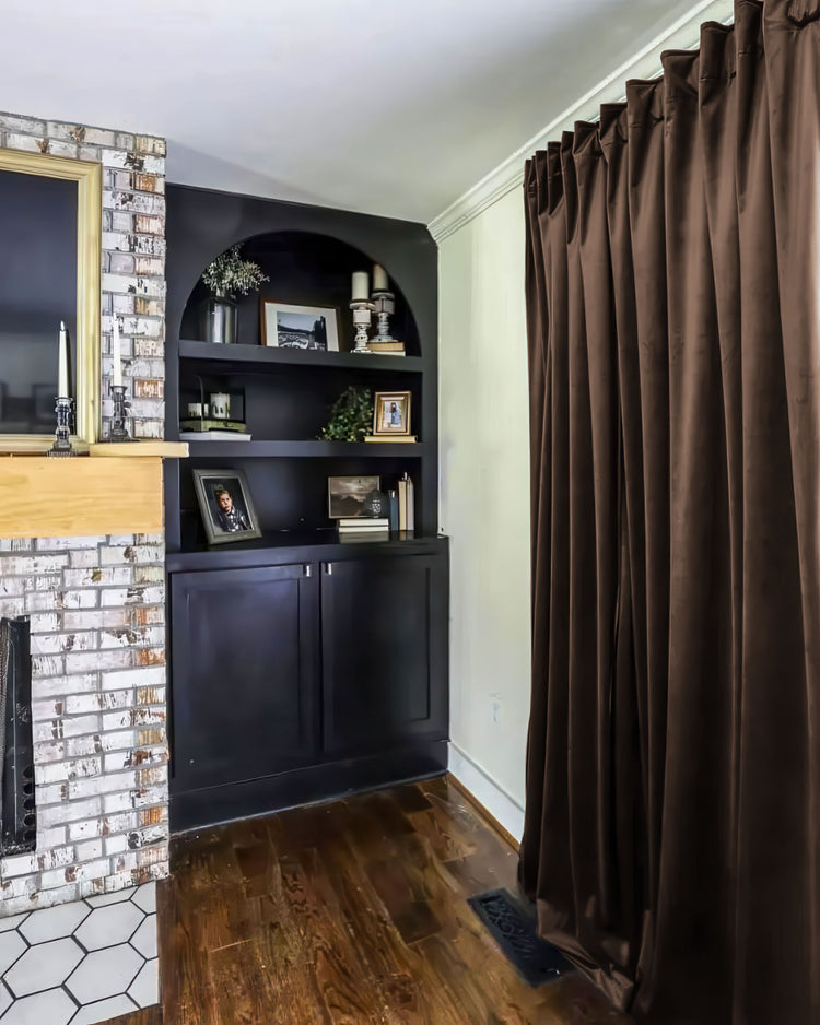 Rich brown custom velvet blackout curtain beautifully installed, enhancing a chic room with a distressed brick fireplace.