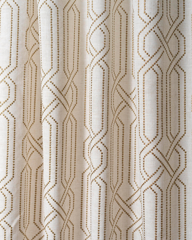 Close-up of Interlace linen blend fabric swatch showing gold dotted geometric embroidery for custom window treatments.