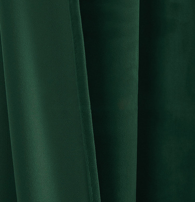 Close-up of luxurious dark green velvet custom curtain fabric, showcasing its rich texture and elegant folds.