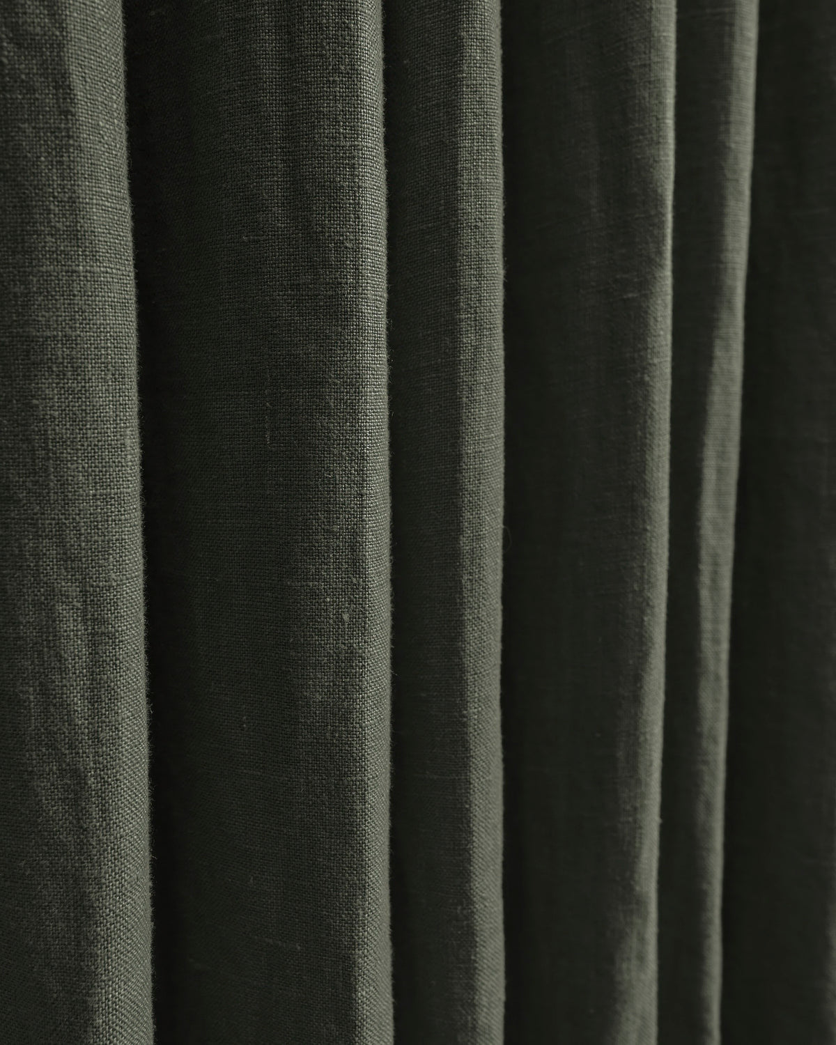 Close-up of deep olive green 100% linen custom curtains, highlighting the natural textured fabric and elegant drapery folds.
