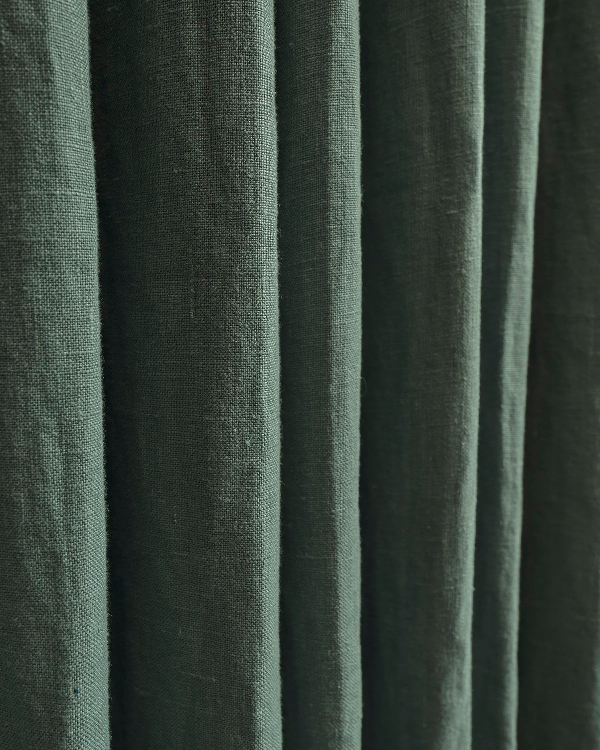 Close-up of Helena 100% pure linen custom curtains in deep green, showcasing rich texture and elegant folds.
