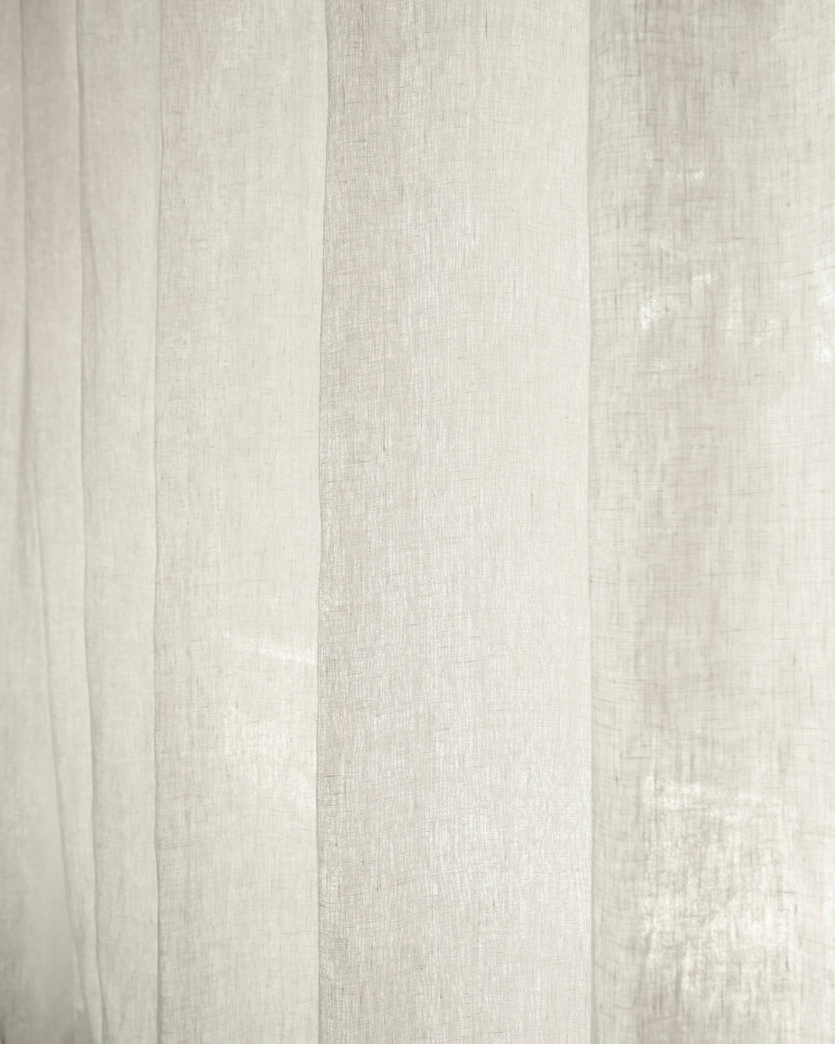 Close-up of soft white Helena 100% pure linen custom curtains, showcasing the light filtering fabric and elegant texture.