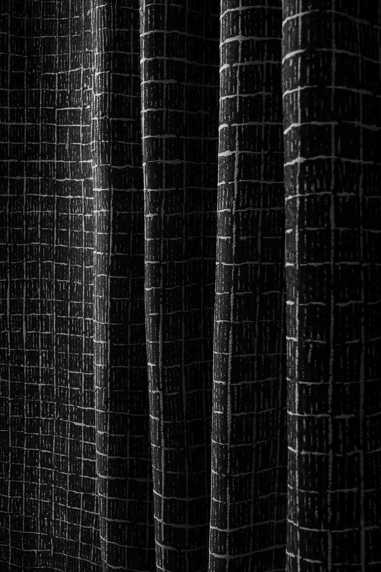 Detailed view of New York Grid patterned textured black fabric for custom outdoor curtain, highlighting waterproof material & elegant folds.