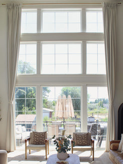 Off-white custom linen blend drapery on tall living room windows, styled with tie-backs for elegant light control.