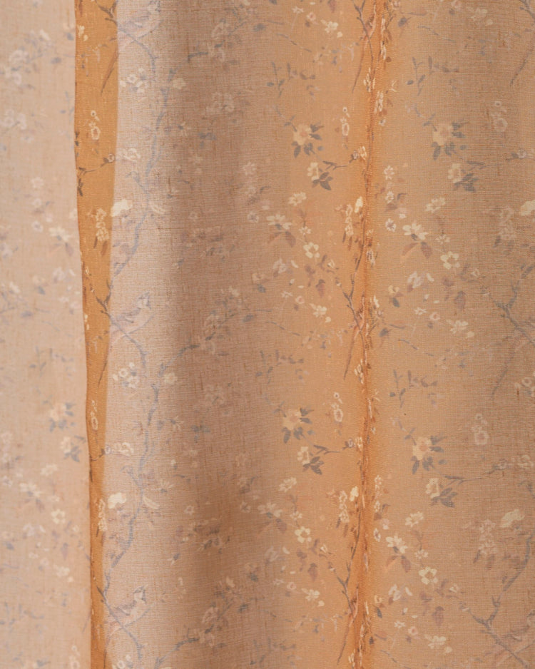 TheHues amber floral patterned sheer fabric for custom window treatments, featuring delicate blossoms on warm orange cloth.