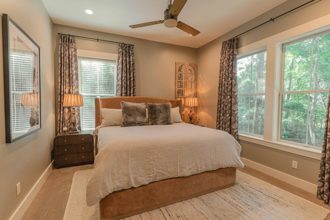 Primary bedroom at Guilford Cottage with patterned floor-length curtains framing two windows
