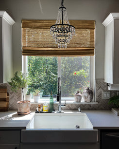 Custom sand Mia Jute Woven Shade installed on a sunny kitchen window, offering natural light and privacy above a farmhouse sink.
