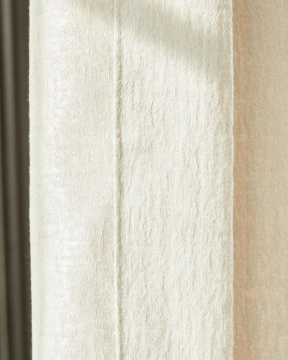 Close-up of cream glint linen blend custom drapery fabric, highlighting its shimmering, textured surface.