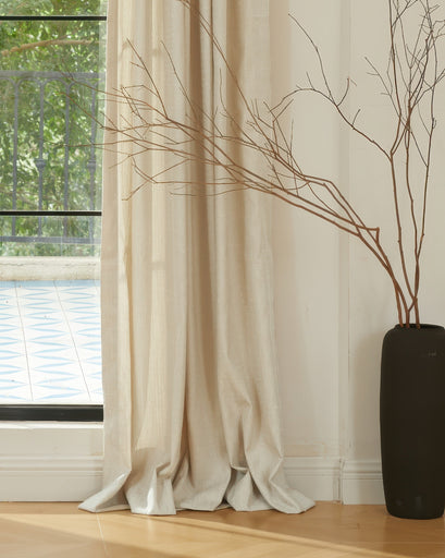 Beige Glint Linen Blend Shimmering Textured Custom Curtain pooling on wood floor next to a large window, enhancing sophisticated home decor.