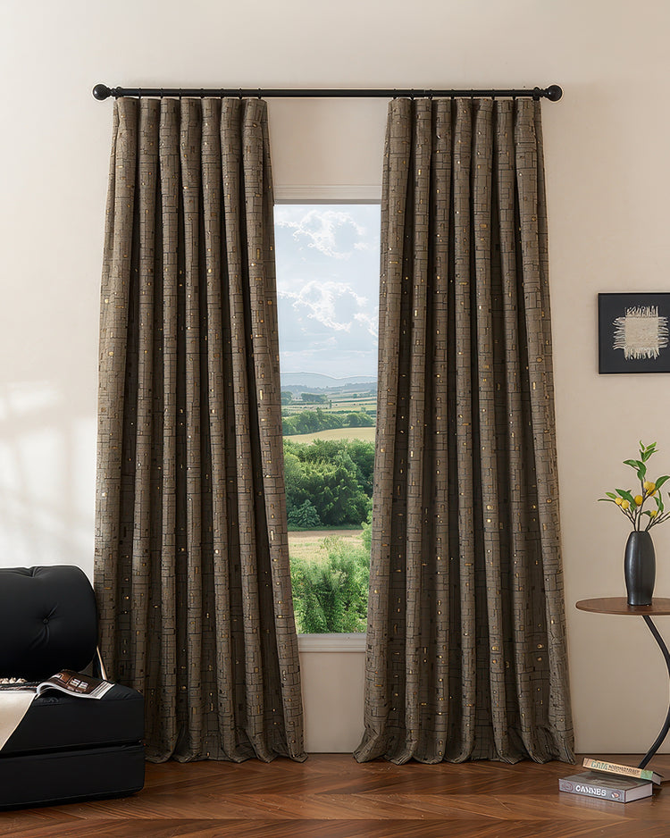 Chelsea custom heavyweight cotton blend patterned blackout thermal curtains in dark gray with gold accents, framing a scenic window.
