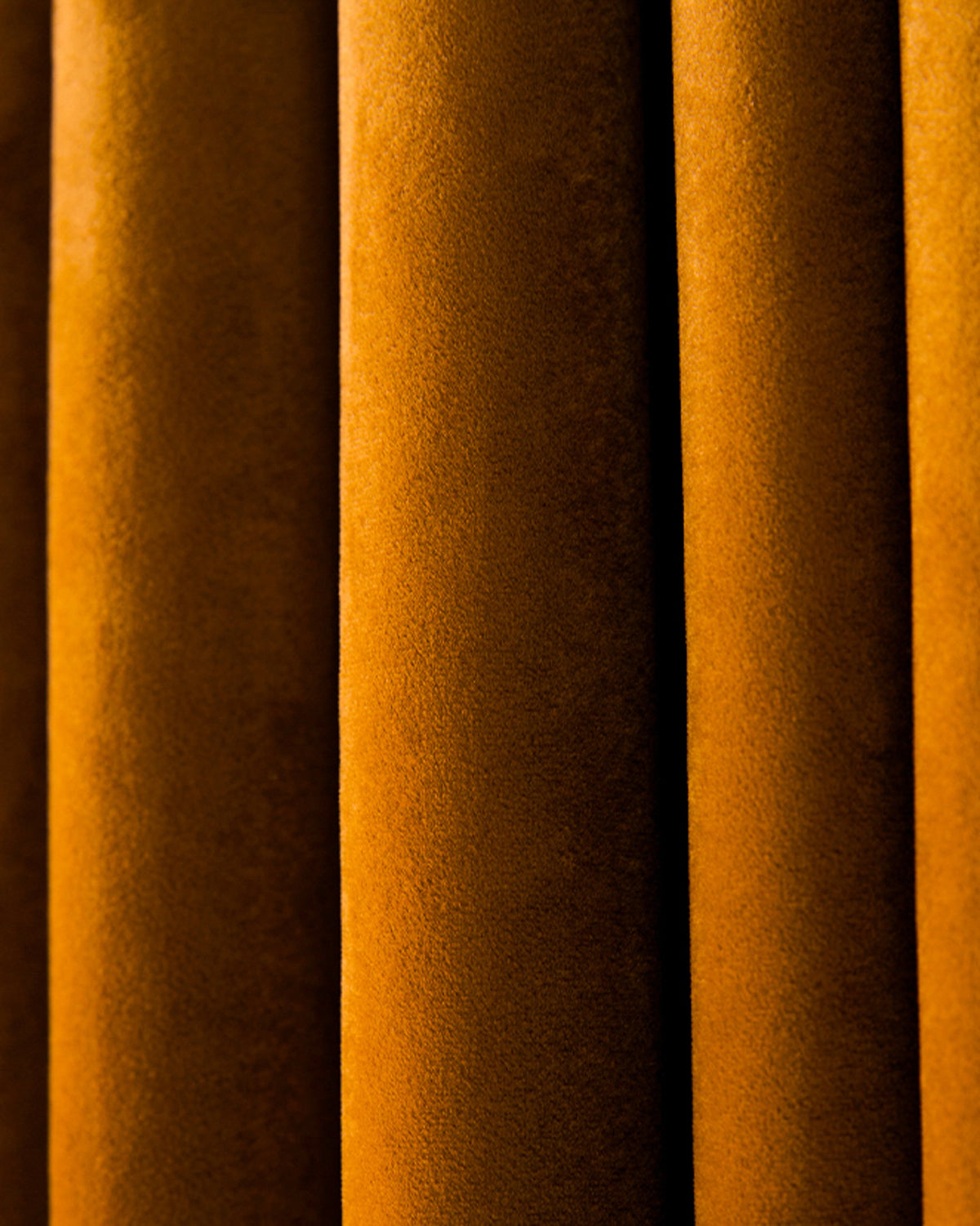 Close-up of elegant Moonlit Velvet custom curtain fabric in deep golden bronze, highlighting plush texture and soft folds for luxurious drapery.
