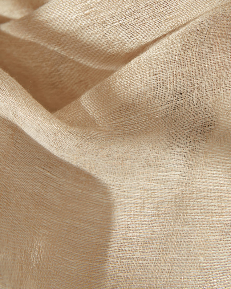 Close-up of light beige linen blend woven sheer curtain fabric, showcasing its delicate texture and soft folds.