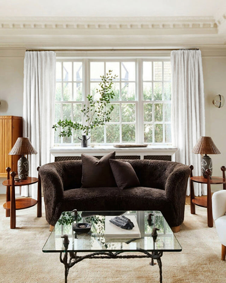 White Voy Linen Look Custom Drapery framing a large window in a sophisticated living room with a dark sofa and glass table.