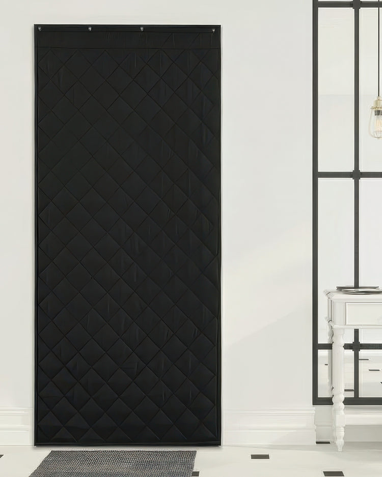 Full-length black quilted custom door curtain, Oxford thermal insulated & soundproof, hanging in a modern home entrance.