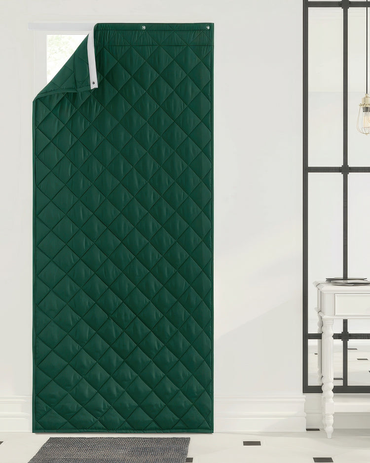 Deep green quilted custom door curtain, thermal insulated & soundproof, with grommet header. Partially open showing a bright window.