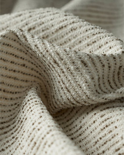Close-up of draped Liwa linen blend custom curtain fabric, featuring textured cream and subtle horizontal brown woven patterned lines.