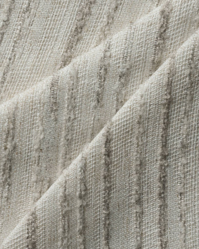 Detailed view of TheHues Sahara Linen Blend custom curtain fabric. Off-white woven base with raised, natural-toned vertical patterned stripes, showing luxurious texture.