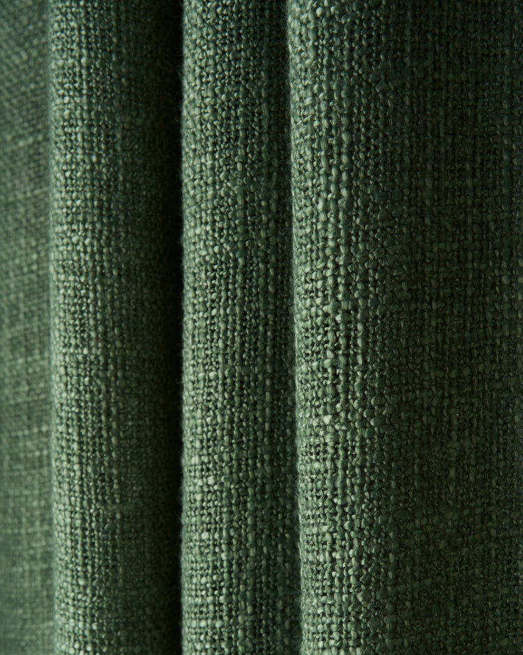 Rich dark green Jupiter pure linen fabric, draped to showcase its distinct woven texture for custom window treatments.