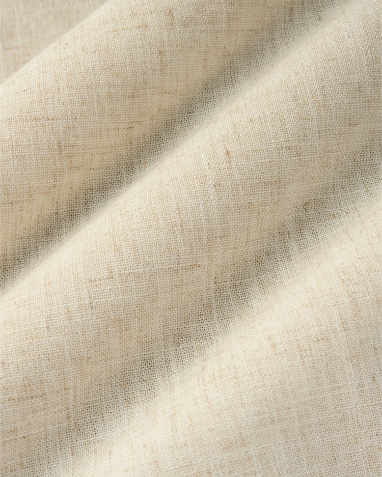 Close-up of custom Breeze linen blend curtain fabric in light beige, featuring a subtle textured weave and flowing folds for elegant drapery.