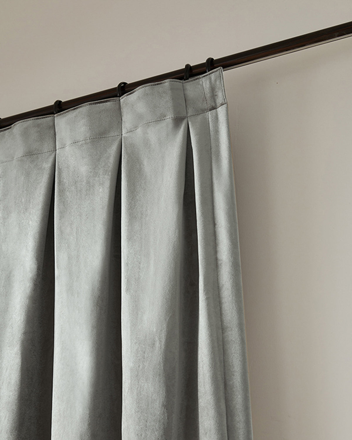 Moonlit gray velvet custom curtain, close-up of tailored pleats on a dark rod. High-end custom drapery for sophisticated home decor.