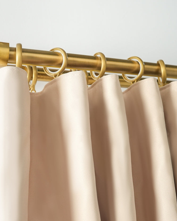 Detailed view of a Roman Bronze curtain rod with silent glide rings, holding pleated cream drapery. Premium home decor hardware.