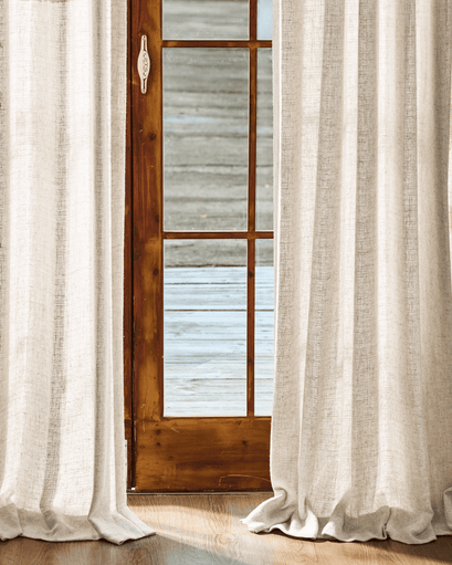 Tailored Fiona Linen Blend custom drapes in light beige, framing a wooden French door & pooling on hardwood. Perfect for light control.