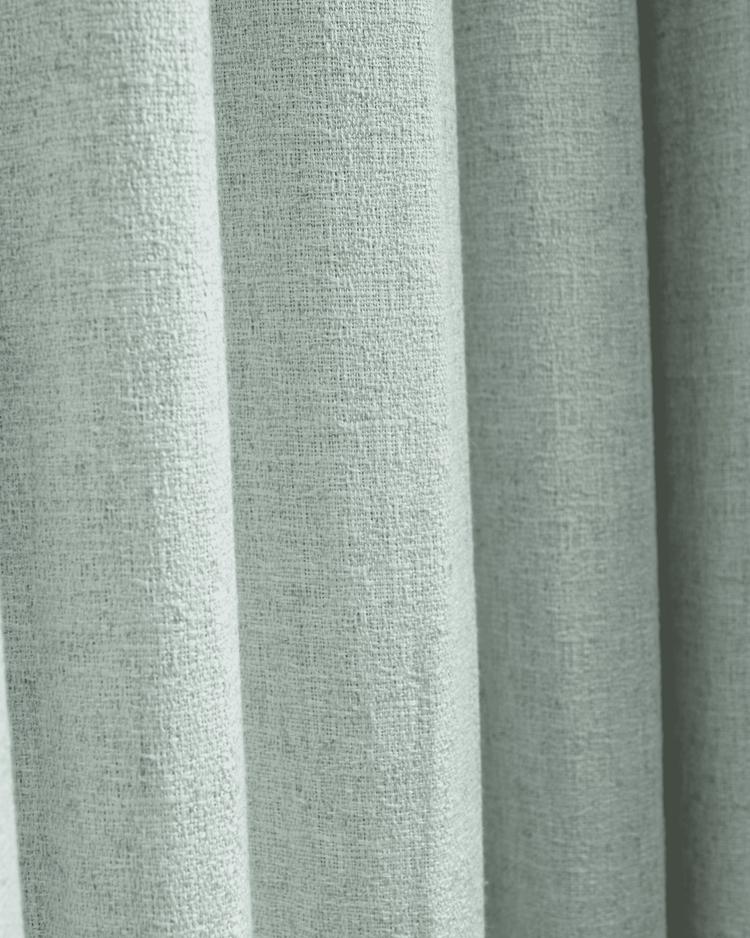 Close-up of the light, textured Fiona Linen Blend custom curtain fabric, showing its intricate weave and elegant vertical folds.