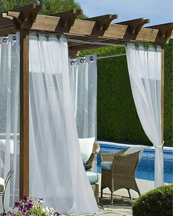 White custom outdoor sheer curtains with grommet tops on a wooden pergola, enhancing a poolside patio with elegant light control.
