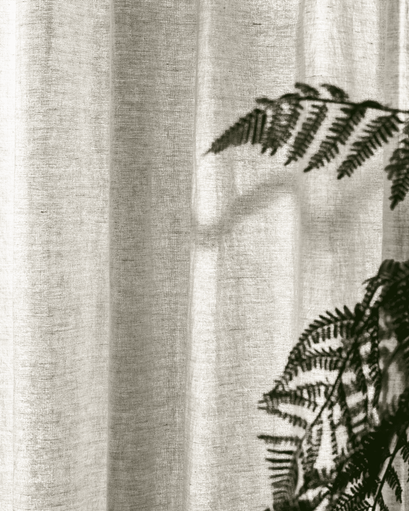 Close-up of a Tahiti 100% pure linen custom curtain, with natural light filtering through & fern shadows accentuating its delicate texture.