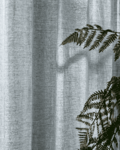 Close-up of sheer light gray Tahiti pure linen custom curtain fabric, highlighting its delicate weave and soft, natural light filtering.