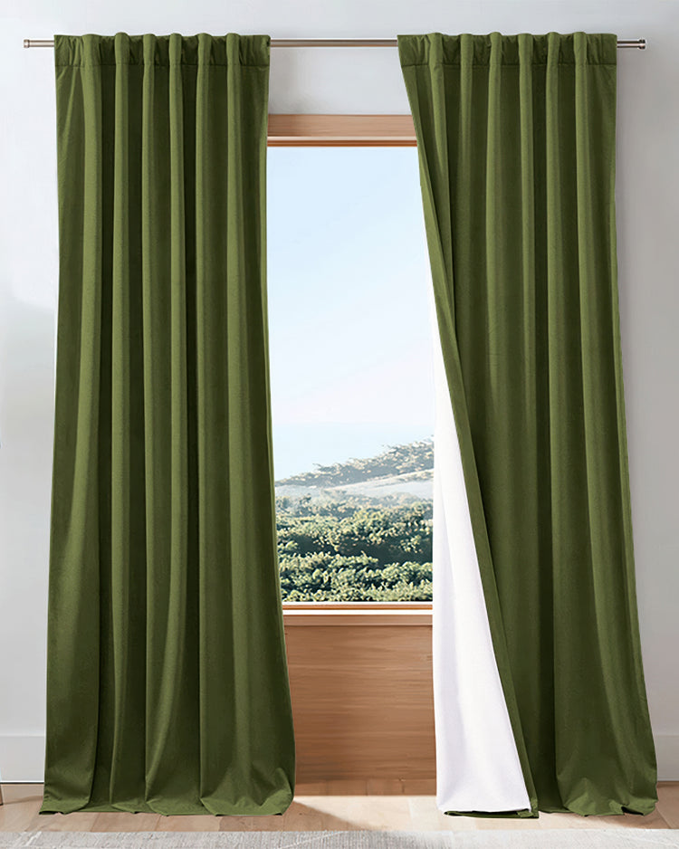 Forest green velvet 100% blackout custom drapery, one panel slightly open revealing white soundproof lining and outdoor view.