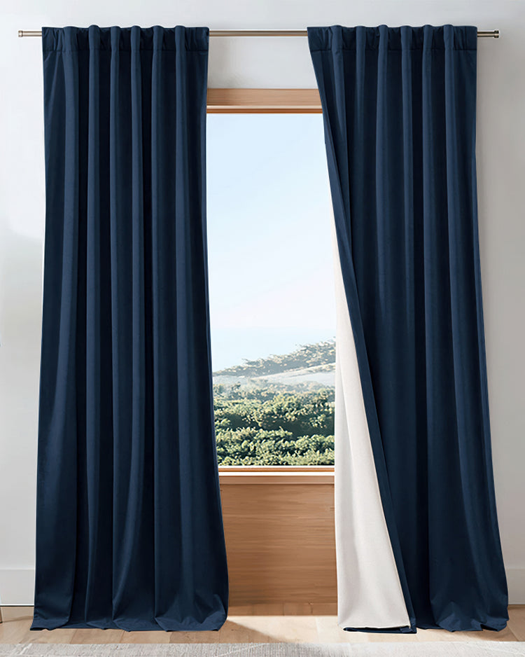 Dark navy velvet heavyweight 100% blackout custom curtains, partly open to show white lining & outdoor view. Ideal for light control.