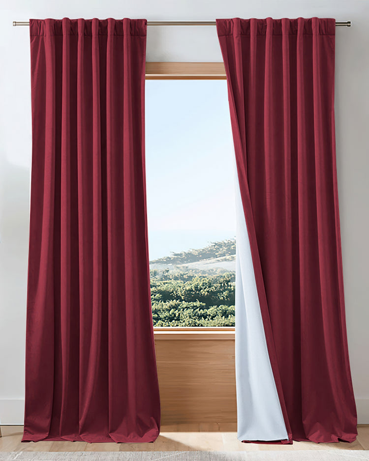 Luxurious red velvet heavyweight custom blackout curtains partially open, revealing white thermal lining and outdoor view.