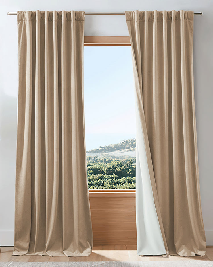 Beige velvet custom blackout curtains, 4 layers heavyweight, slightly parted to reveal white thermal lining & outdoor view.