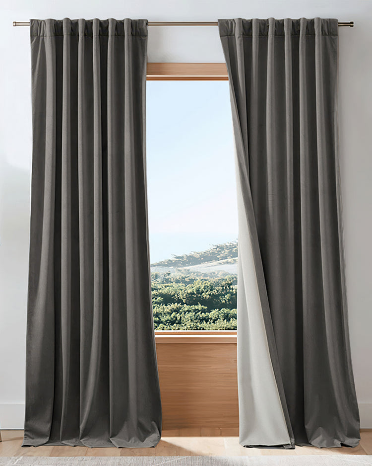 Dark grey custom velvet drapes with elegant pinch pleat header, revealing thick blackout lining & outside view.