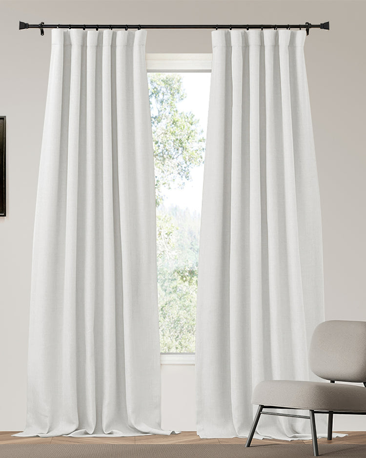 White linen-look custom blackout drapery panels with elegant pinch pleat header on a dark rod, balancing light control & privacy.